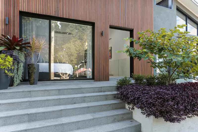 Timber-clad entry approached by wide stone steps and layered planting