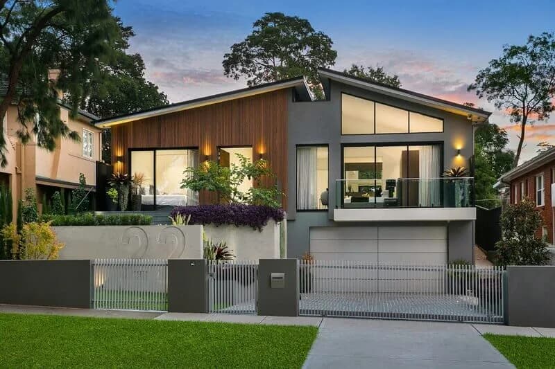 Hunters Hill Residence street elevation with timber cladding, broad glazing, and terraced landscaping at dusk