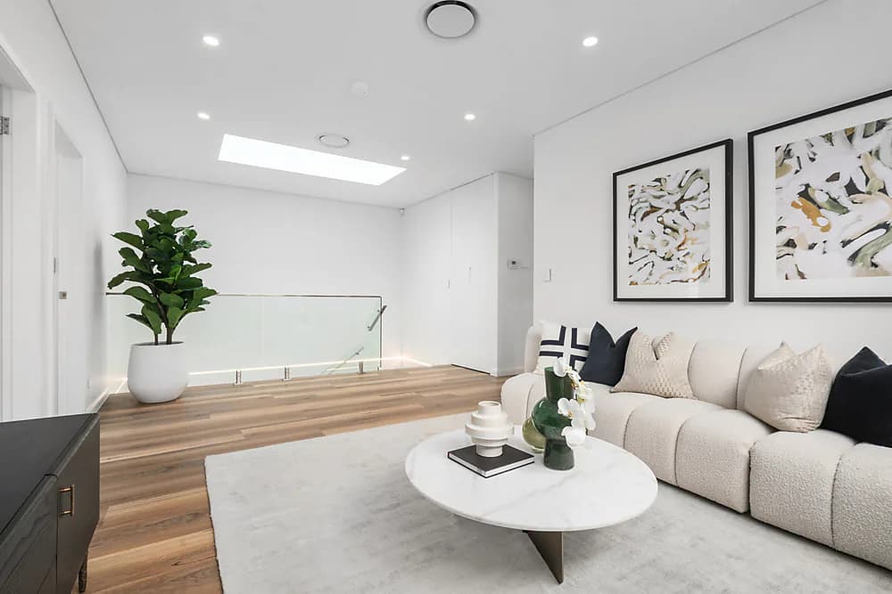 Living room with timber flooring, skylights, and a glass balustrade