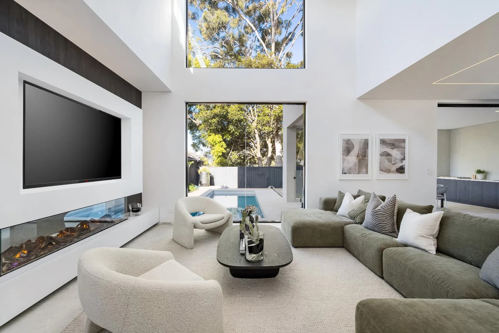 Double-height living room with a tall picture window and pale stone fireplace